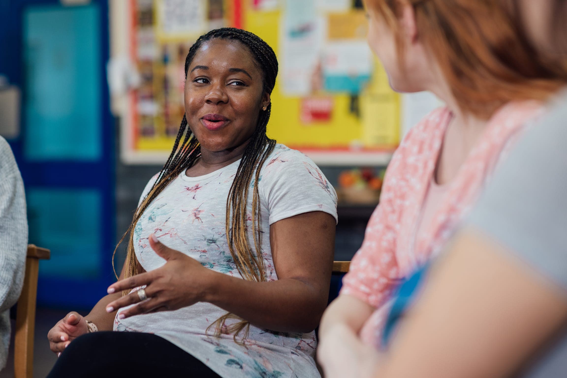 A woman smiling and talking during a group session in a classroom.