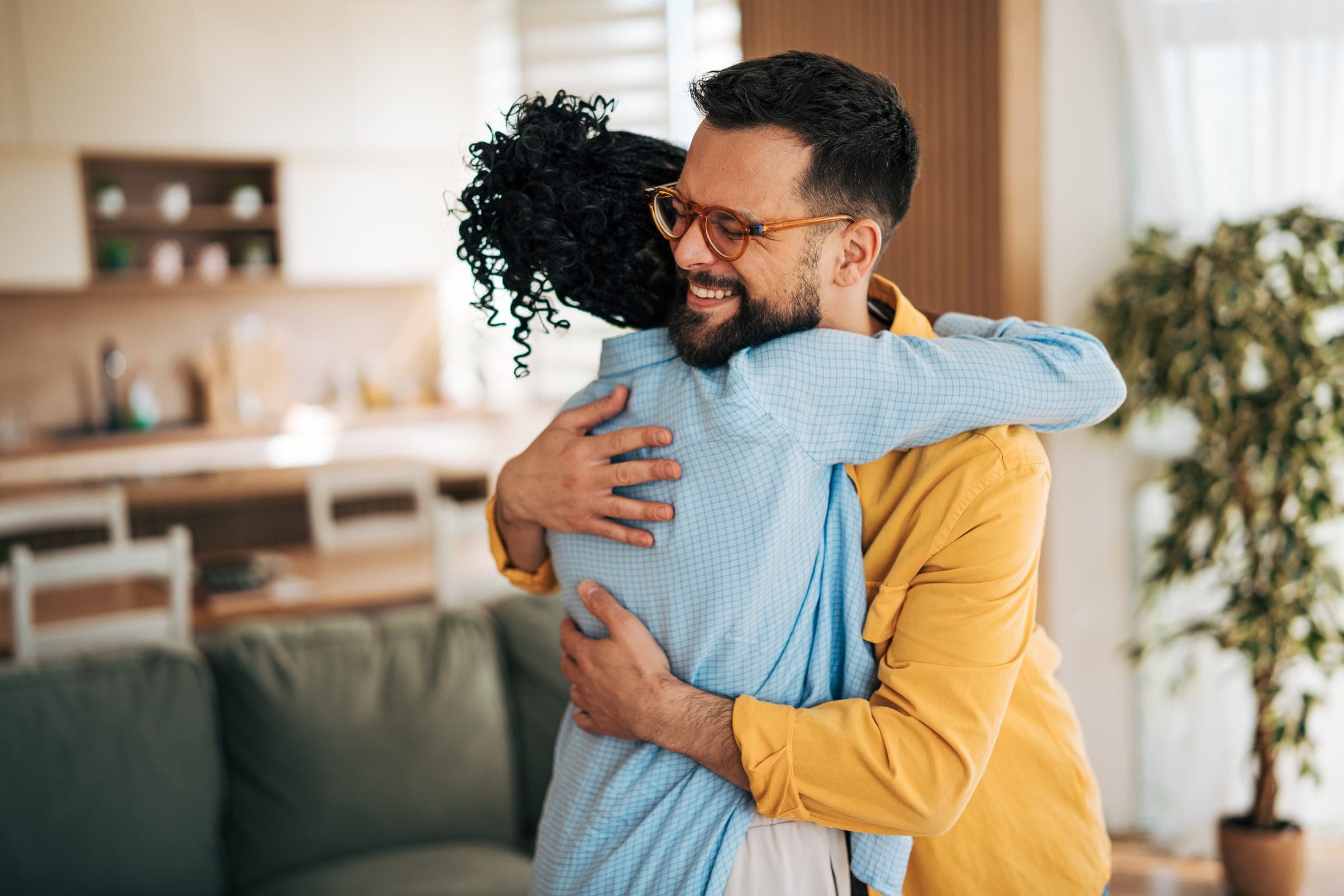 A man and a woman hugging in a kitchen at home.