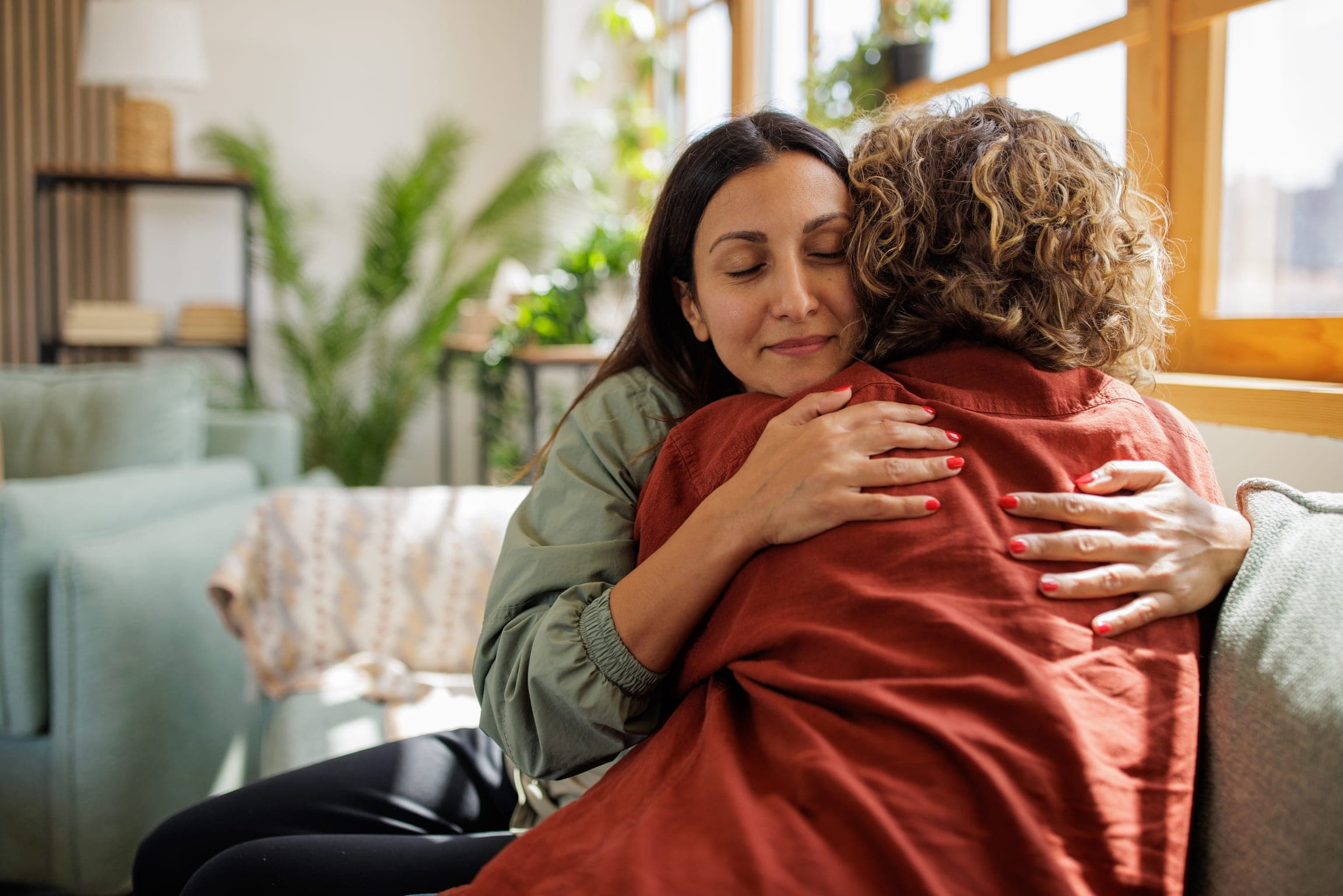 Two women embracing in a living room.
